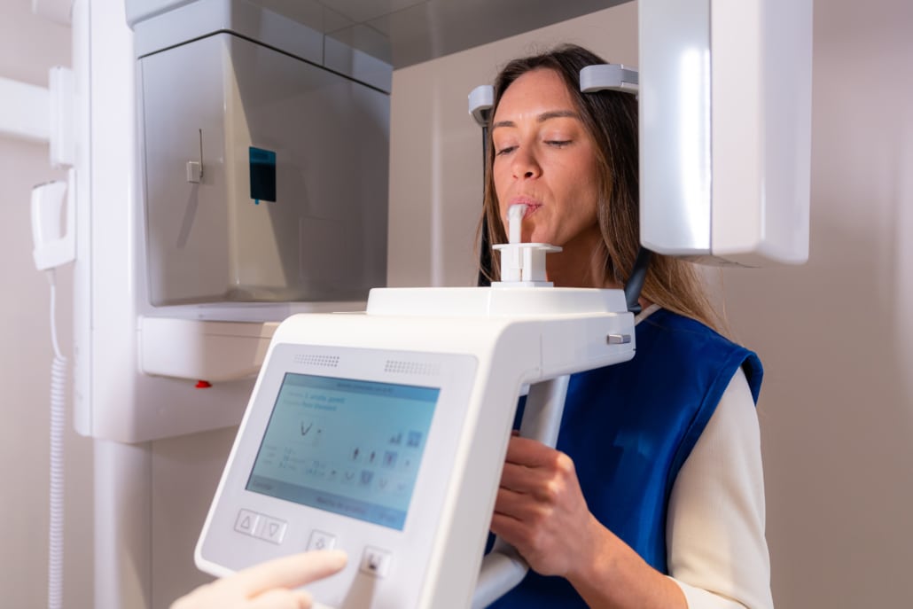 Mulher utilizando um moderno equipamento de radiografia odontológica numa clínica dental. O equipamento é essencial para o planejamento preciso de implantes dentários com carga imediata, garantindo uma colocação segura e eficaz do implante.