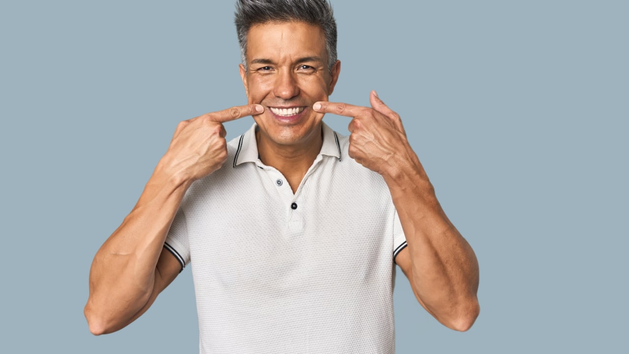 homem apontando para o sorriso com implante dentário